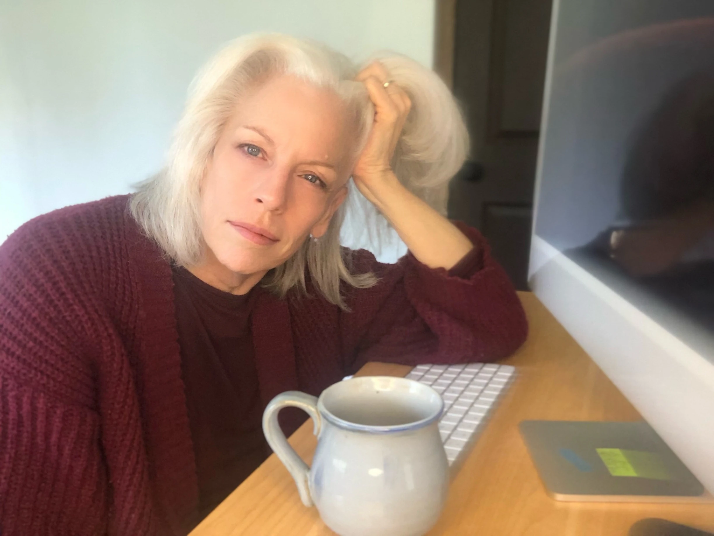 Pinkerton at her desk with coffee, looking tired but functional